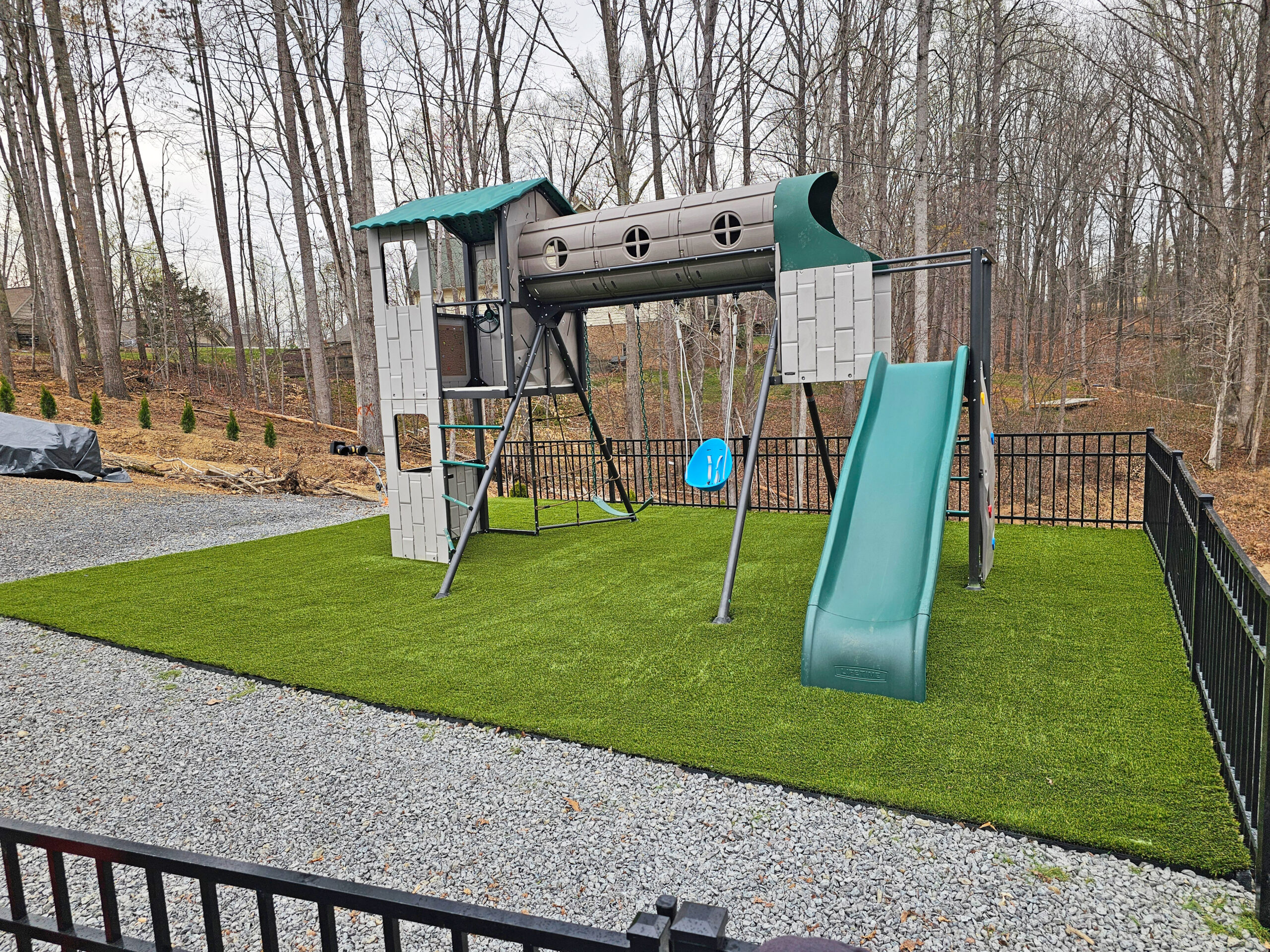 A newly installed Synthetic Turf Backyard Playground alongside a serene water body, blending natural beauty with playful design.