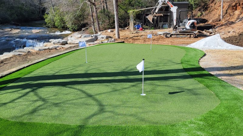 Stunning view of a newly installed artificial turf putting green in Walhalla, enhancing the backyard with its proximity to natural water and rocks.